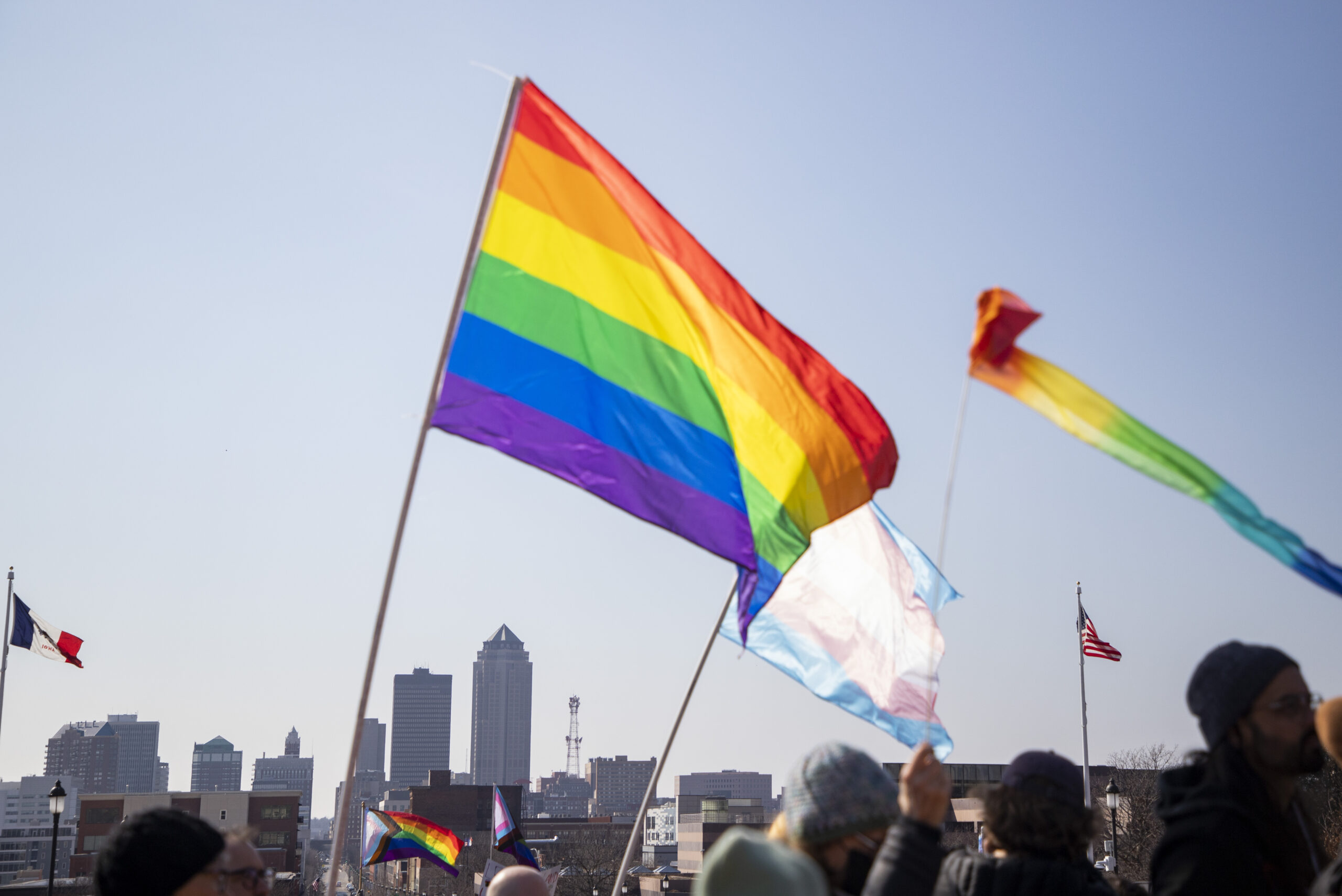 Rainbow LGBTQ pride flags fly in the foreground of the Des Moines skyline.