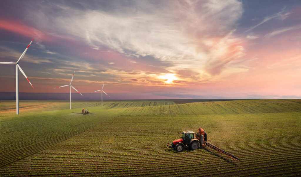 Tractor working field with windmills Getty