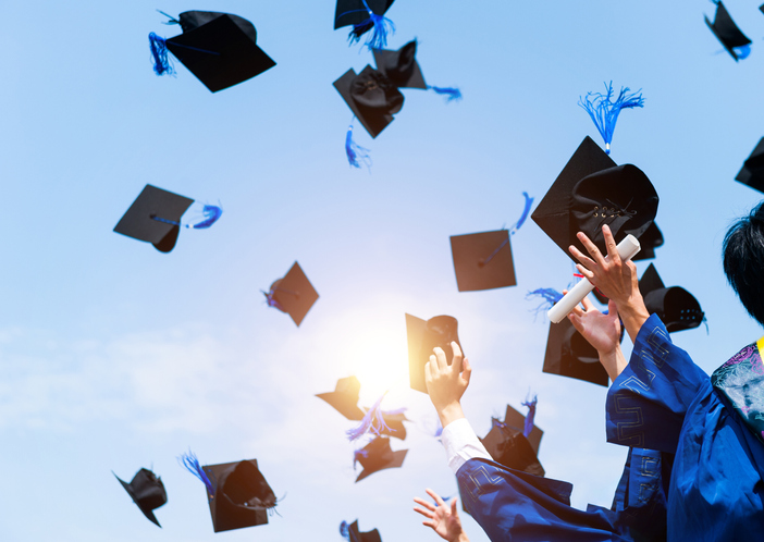 Graduation caps in air Getty