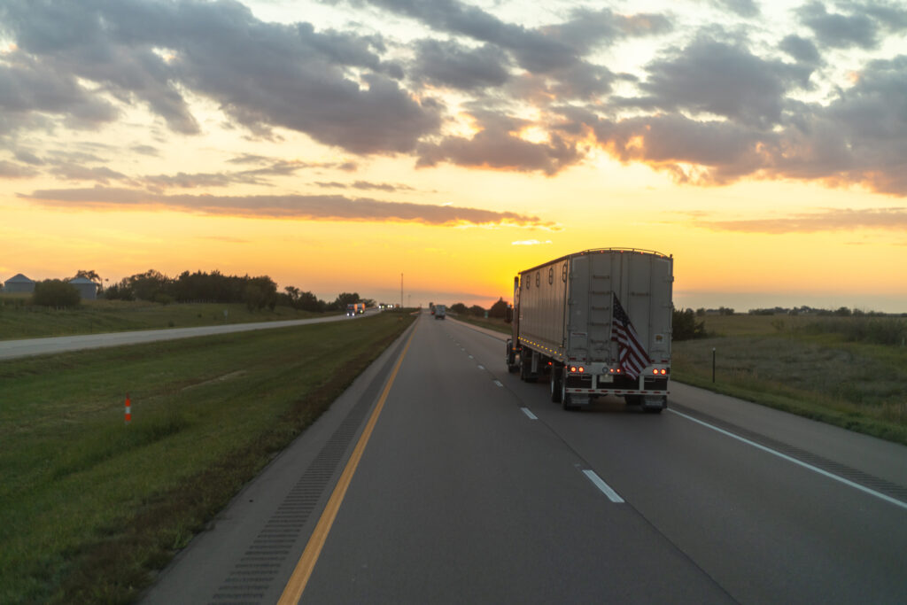 Semi truck driving along a highway under a stunning sunset sky, showcasing the beauty of long hauls.
